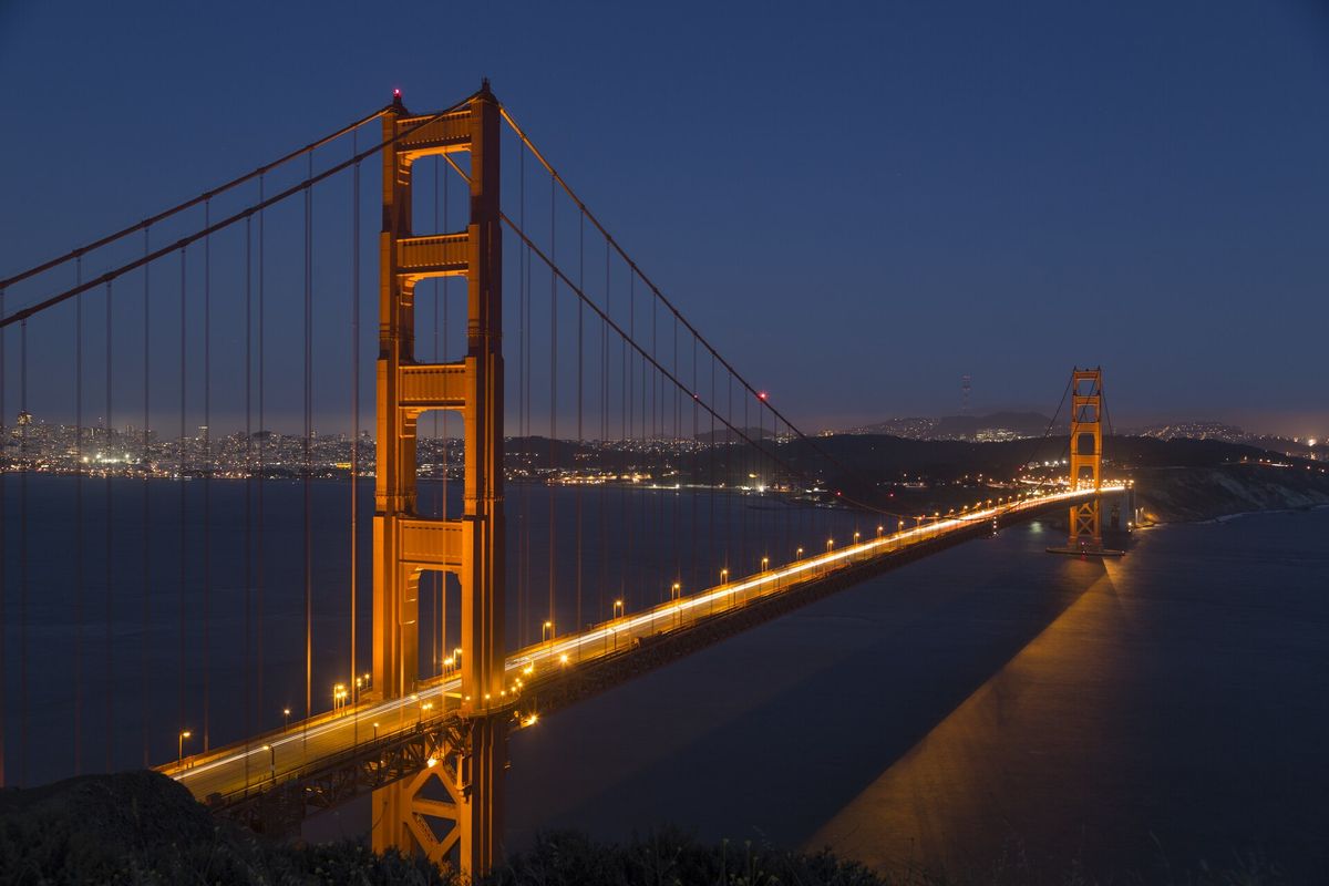 The Golden Gate Bridge lit up at dusk, with San Francisco behind it
